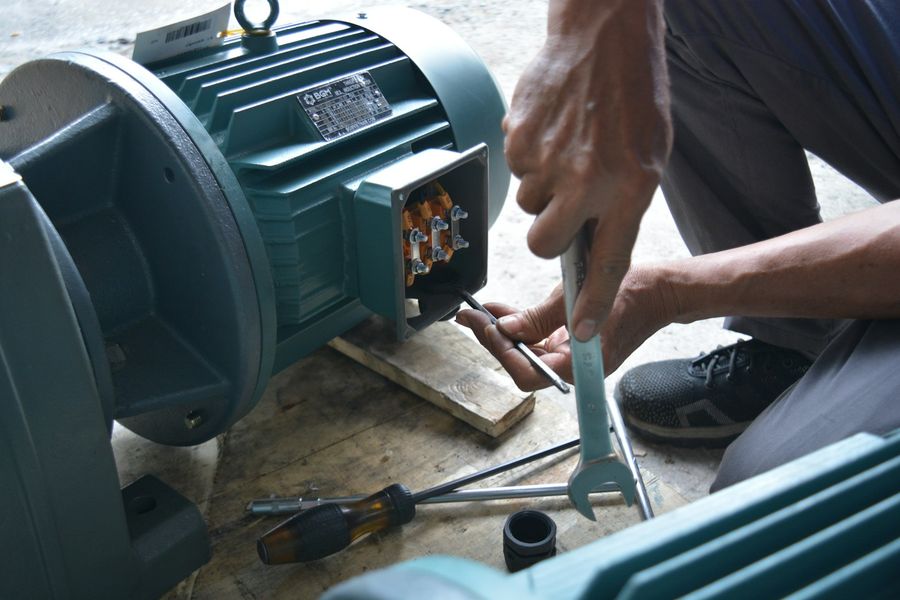 Mãos de um técnico ligando o terminal de um motor elétrico